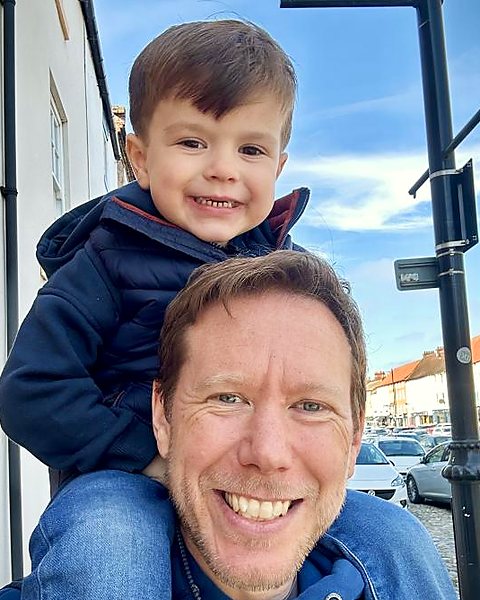 James Mills smiling at the camera with his son Hudson sitting on his shoulders, on Yarm high street.